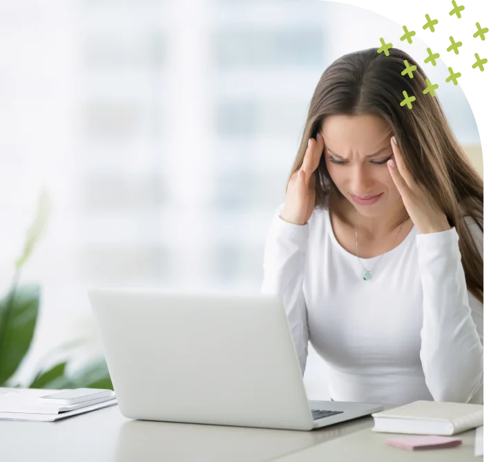 Frustrated woman holding head in front of laptop